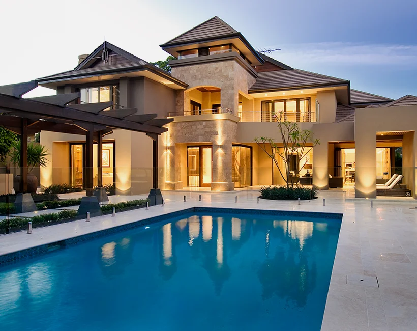 Luxury two-storey home with tiled roof, stone facade, large windows, and poolside outdoor living area